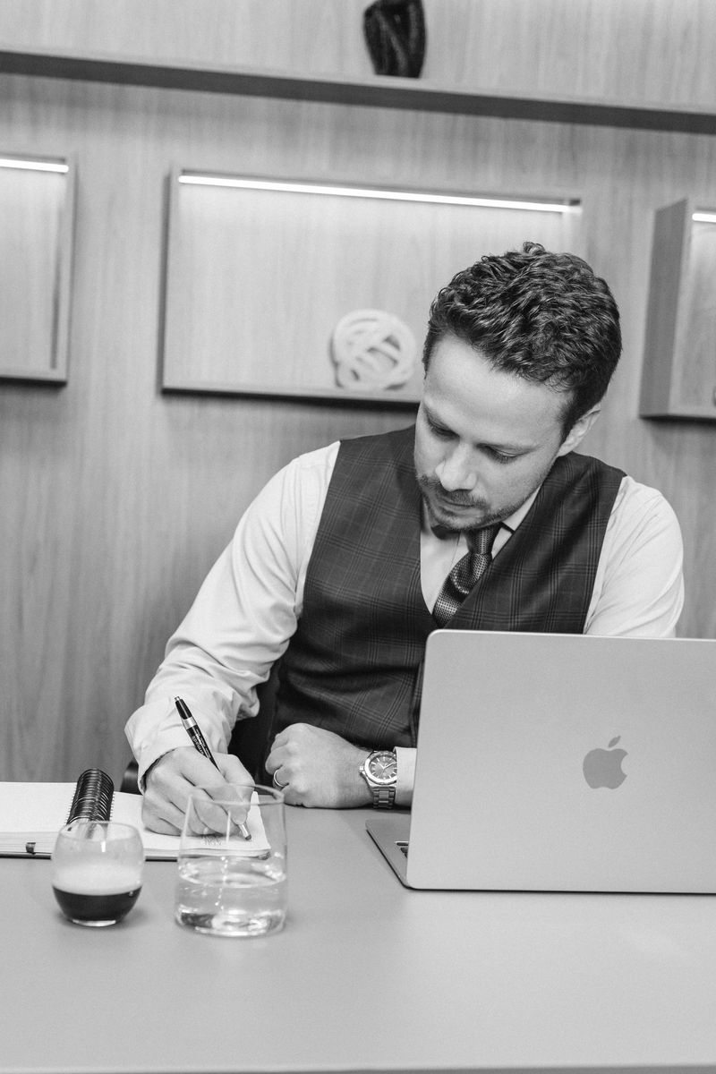 André Cavalcante escrevendo à mesa, em preto e branco